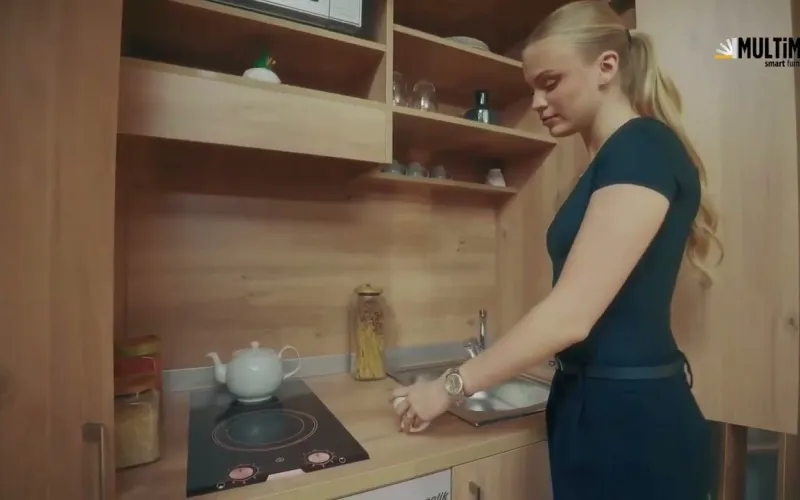 Secret Kitchen | Video Description: A presenter opens a compact cabinet unit and demonstrates how it unfolds into a complete kitchen with worktop, sink, cooktop and storage, then closes it back into a flush cabinet front - a smart kitchen that creates space for those who say there is no room at home.